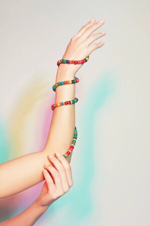 Female hand with bracelets against the light colored spotlights backgroundの写真素材