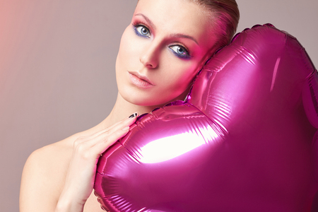 beautiful blond woman with balloon heart.romantic young lovely girl with short hair and colorful male-up. heart,love,Valentine's Dayの写真素材