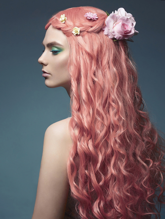Beautiful girl with long pink hair and flowers in them. Fabulous spring portrait of young woman with make upの写真素材