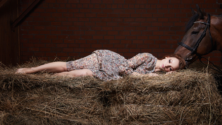 Beautiful young woman with a horse.sensual girl and horse in haysloftの写真素材