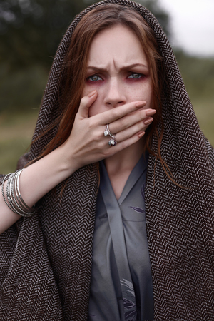 young woman in hood With hand closed mouth. outdoor portrait
