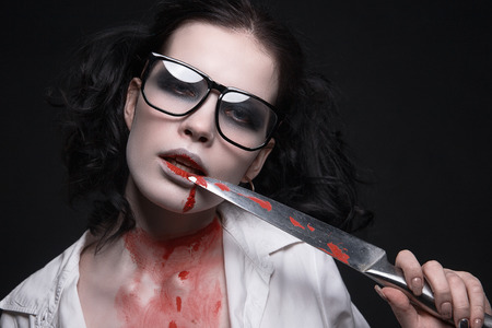 sexy student girl all in the blood with a knife.halloween make-up beautiful woman