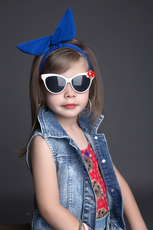 funny child girl in big blue bow and sunglasses. children shopping. fashionable little girlの写真素材