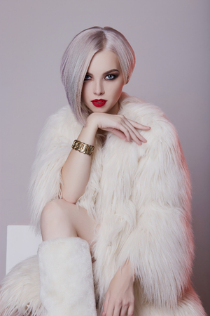 Beautiful blond young woman in white fur.winter fashion.Beauty sexy Model Girl with bob hair and make-upの写真素材