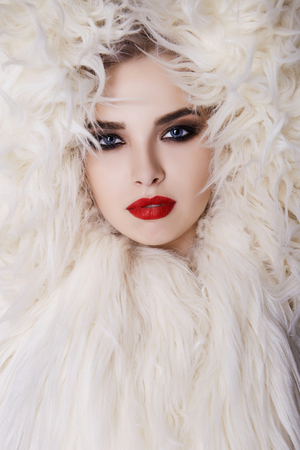 Beautiful young woman in fur.winter fashion beauty girl model in hood and red lips make-upの写真素材