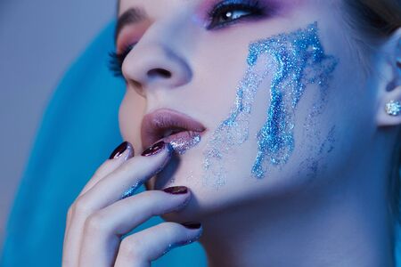 beautiful young woman with make-up and blue liquid gloss on her face.make up conceptの写真素材