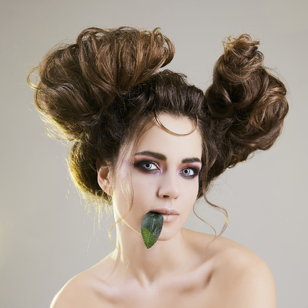 beauty portrait, young woman with make-up and Hairstyle. summer style beautiful brunette girl with a sheet in the mouthの写真素材