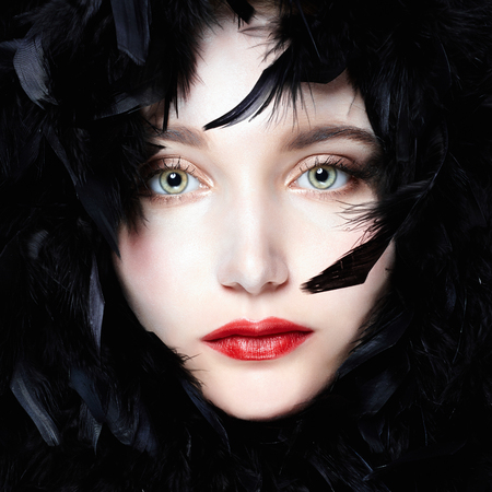 face of beautiful young woman in feathers. Feathers hat girl with make-upの写真素材