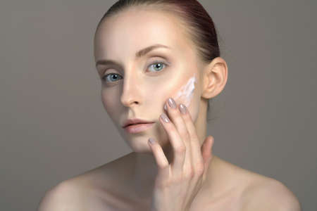 beauty portrait of young woman girl applying cream on the face. beautiful model girl without...