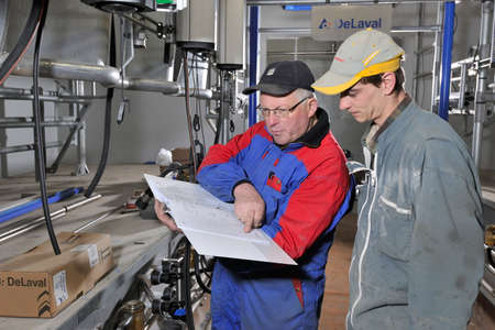 Normandy, France, march 2013.
Installation of a new milking parlour in a dairy farm. Installation technician and farmer examining the plansのeditorial素材