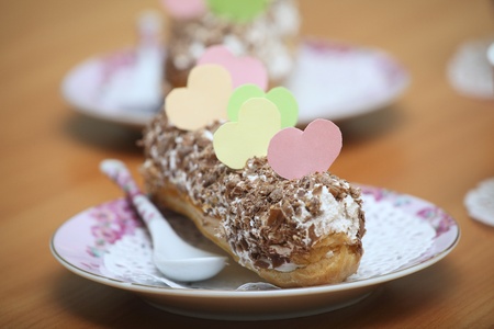 Served eclairs for a couple on a wooden table with paper hearts