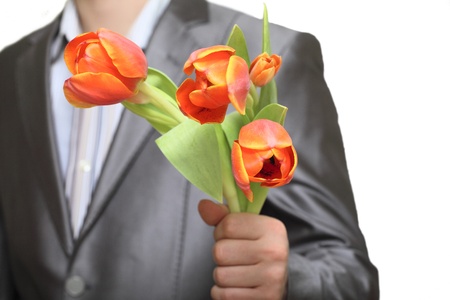 Male hand in suit coat with bunch of tulips as presentの写真素材