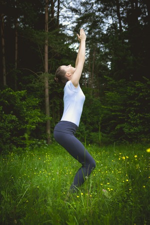 Woman doing utkatasana outdoors in the forestの写真素材