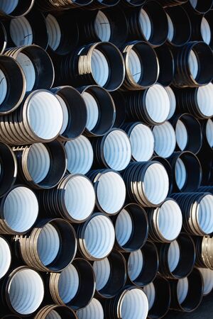 stacks of black pvc plastic pipe outdoors outside the warehouse