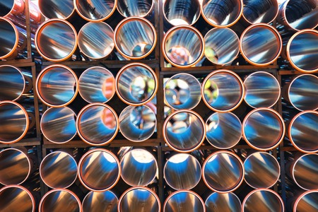 background of colorful big orange plastic pipes for hot water used at the building site close-up stack of pvc outside warehouseの写真素材