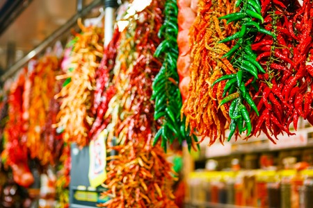 Hot chili peppers green, orange, red, yellow colors at the market hangingの写真素材