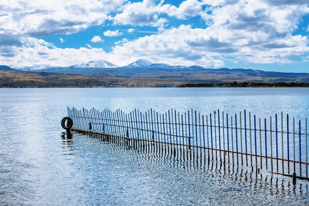 the view on mountains from the pier of Sevan lake and white clouds on blue sky on a sunny day, Armeniaの写真素材