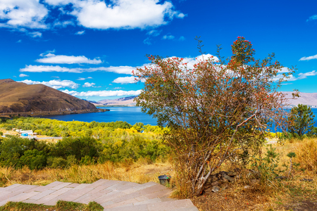 the view on mountains from the pier of Sevan lake and white clouds on blue sky on a sunny day, Armeniaの写真素材