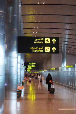 Doha, Qatar - 14 February, 2017: Interior of Hamad International Airport Terminal. Arrival transfer signs. Woman passanger walk with the suitcase lagguage carry onのeditorial素材