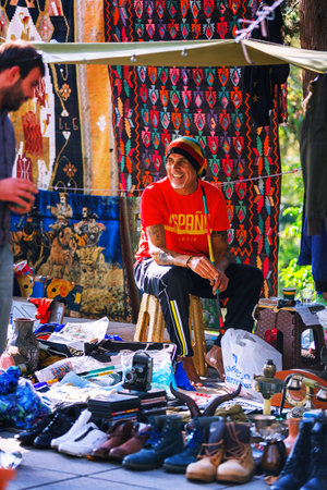 Tbilisi, Georgia - 08 October, 2016: An unidentified rastafari seller on Dry Bridge Flea market in Tbilisi sells Soviet badges and icons, retro junk stuff, tableware set, dishesのeditorial素材