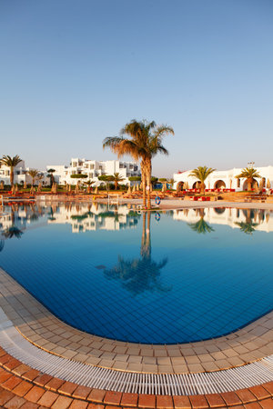 Hurgada, Egypt - 14 August, 2014: Pool on a tropical beach, reflection of palm tree in the water - vacation backgroundのeditorial素材