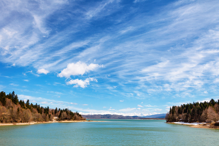 Frozen crystal blue lake and snowy woodland in winter Georgia. Shaori lake, Racha. Caucasus. Colorful vibrant outdoors on a sunny dayの写真素材
