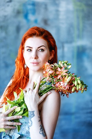 Charming romantic female woman holds Gloriosa Orange on blue background. Flower shop and floristic...