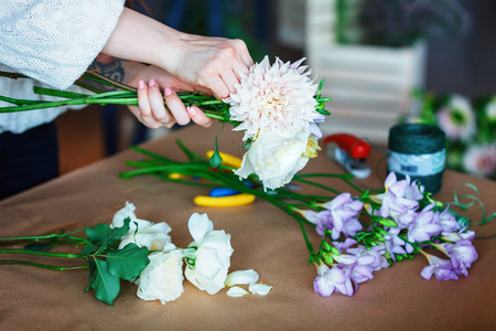Close up shop assistant making bouquet with purple crocus and roses, Eucalyptus poplaraceous populus and Chrysanthemum single-headed Anastasia white. floristic design master class conceptの写真素材