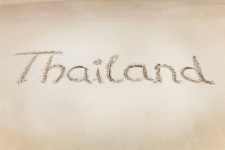 The Thailand letters word written on the beach sand. Crystal blue water of the seaの写真素材
