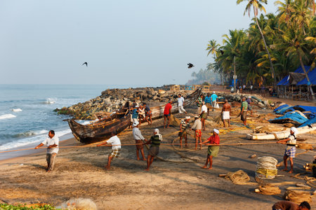 Varkala, India - February 09, 2016: Fishing net with many fishermen on backside the boat. Odayam beach, Varkala, Indiaのeditorial素材