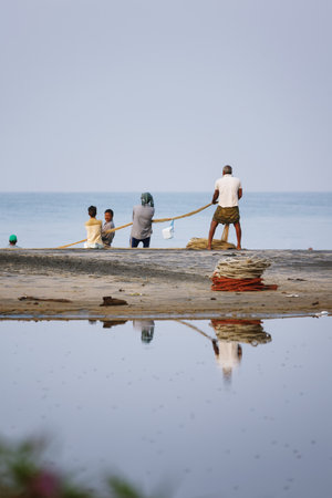 Varkala, India - February 09, 2016: Fishing net with many fishermen on backside the boat. Odayam...