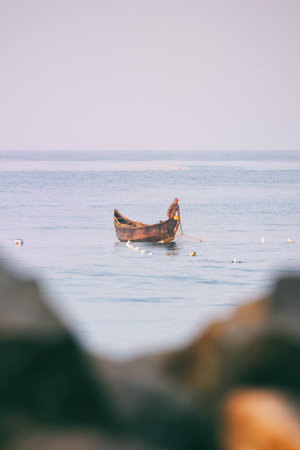Varkala, India - February 09, 2016: fisherman standing and sighting fish in traditional wooden canoe boat on blue indian ocean during morning catchのeditorial素材