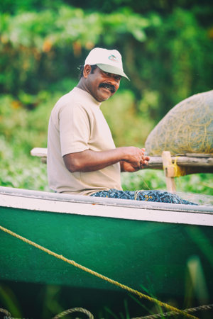 Kollam, India - February 14, 2016: Portrait of happy Indian fisherman unravels fishing nets and tackle while sitting in a boat, Kerala India Fishery Gulf, Man Conceptのeditorial素材