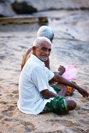Varkala, India - February 09, 2016: Portrait of happy Indian fisherman unravels fishing nets and tackle while sitting in a boat, Kerala India Fishery Gulf. Odayam beach, Varkala, Indiaのeditorial素材