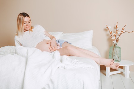 Pregnant mothercare lifestyle concept, Bob hairstyle blond woman health care. white light interior,...
