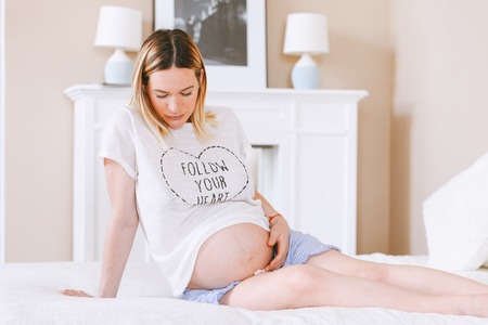 Pregnant mothercare lifestyle concept, Bob hairstyle blond woman health care. white light interior,...
