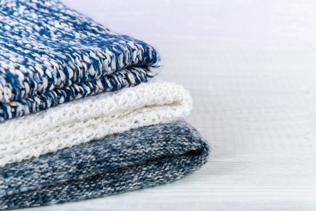 Wool socks and stack of various sweaters. Winter style. On a wooden table, handmadeの写真素材