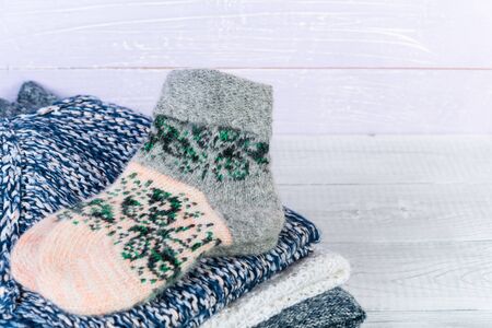 Wool socks and stack of various sweaters. Winter style. On a wooden table, handmade