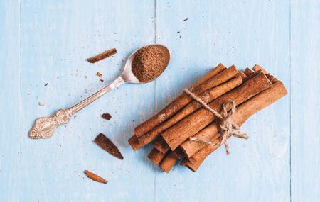Ground cinnamon, cinnamon sticks, tied with jute rope on old wooden background in rustic style selective focusの写真素材