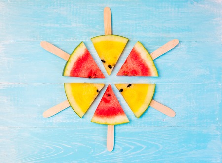 Sliced red and yellow watermelon on old blue tableの写真素材