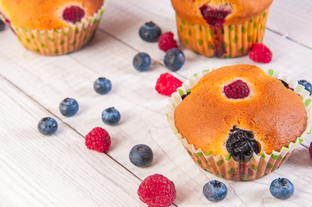 Blueberry and raspberry muffins with powdered sugar and fresh berriesの写真素材