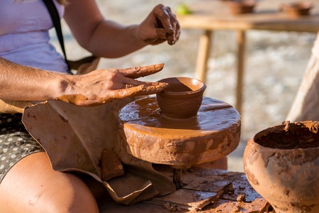 Potter hands making in brown clay on pottery wheel. Potter makes on the pottery wheel clay pot.の写真素材