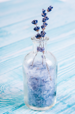 Homemade cosmetic infused lavender salt in a glass bottle standing on a wooden boardの写真素材