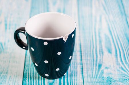 Broken black ceramic cup, blue wooden background, free spaceの写真素材