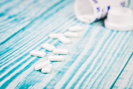 White tablets and bottle for tablets on blue background.Free space for text.