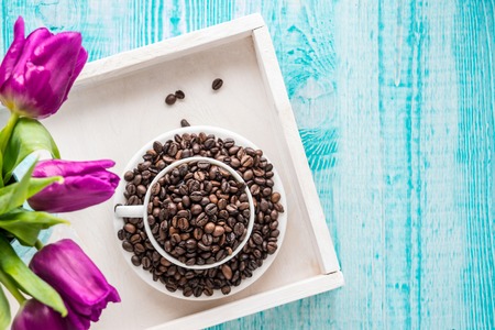 Vintage wooden tray with porcelain cup full of coffee beans and pink flowers on shabby chic mint background, top view point. Copy space for text, Woman day. love conceptの写真素材