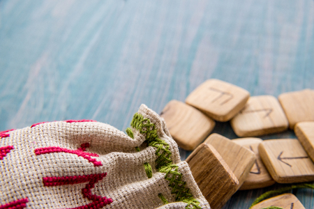 Ancient runes, canvas bag with embroidery on old vintage wooden background. Selective focus.