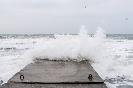 Sea strong storm waves crashing on stone pierの写真素材