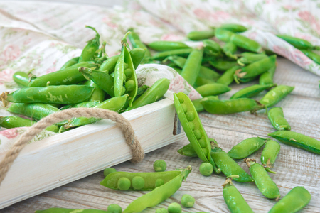 Pods of green peas outside on a wooden tableの写真素材