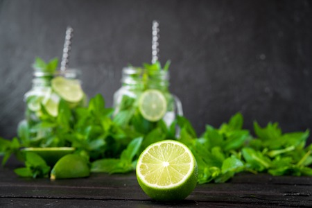 Mojito cocktail with lime and mint in highball glass on a black stone background Copy space.の写真素材